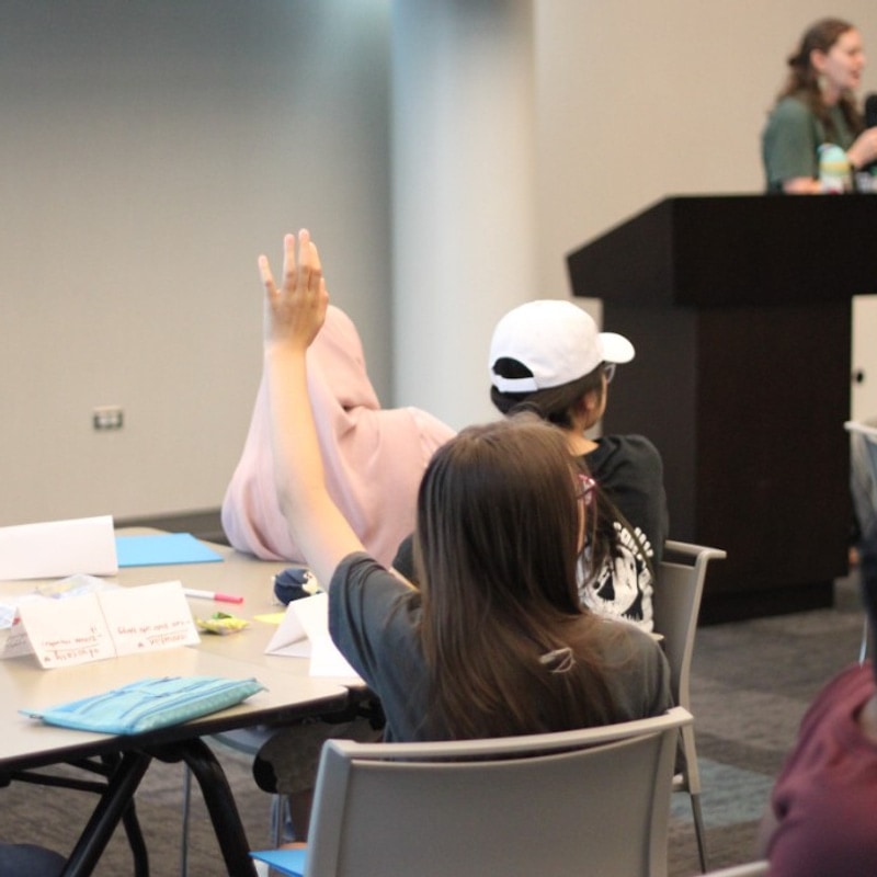 Student raising their hand during a guest speaker session at Session 3